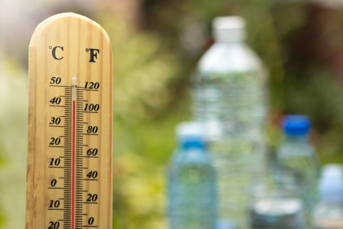 Ein Thermometer steht neben drei Wasserflaschen