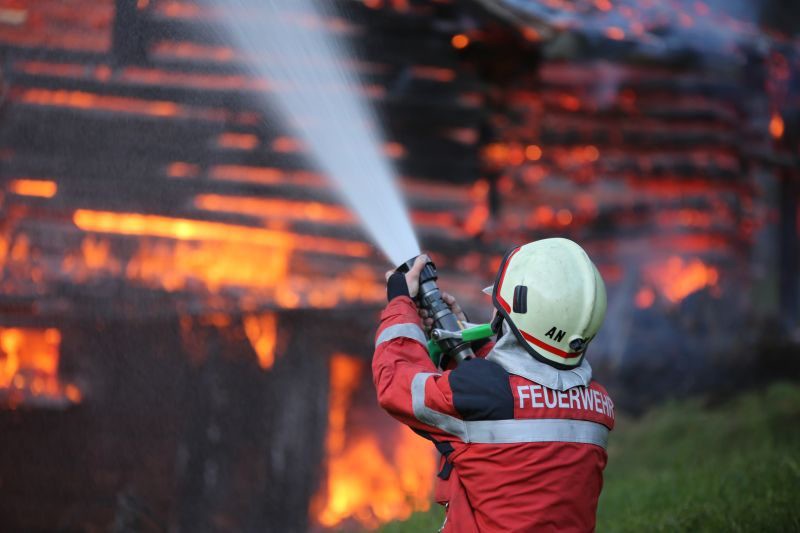 Ein Feuerwehrmann löscht eine brennende Scheune.